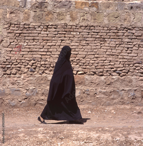 A veiled Muslim woman walks on a Sana a street in Yemen