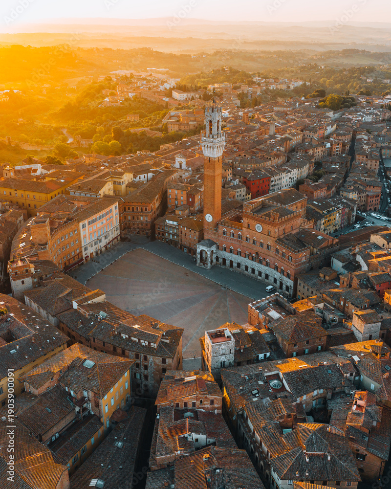 Naklejka premium Aerial view of Siena historic center with the iconic Piazza del Campo illuminated by warm sunset light