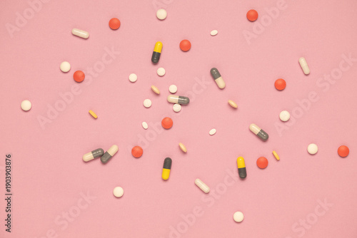 Multiple shapes and sizes of pharmaceutical medications on a pink background.  Polypharmacy concept.