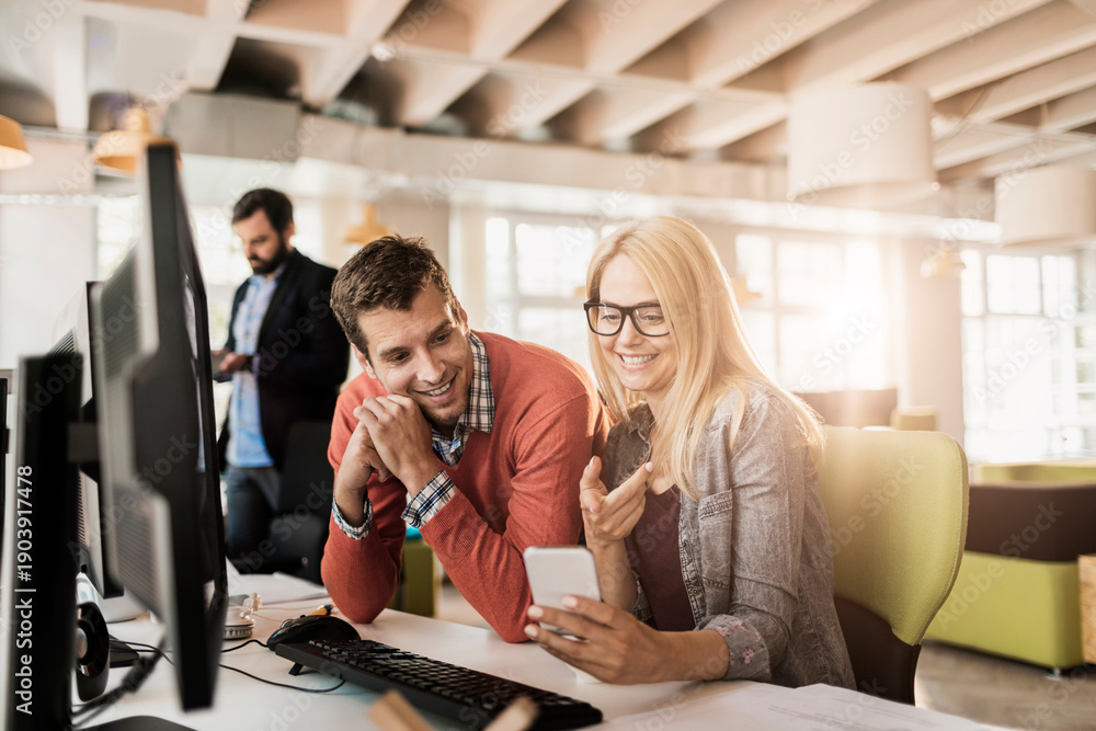 Fototapeta premium Coworkers collaborating with smartphone in modern office