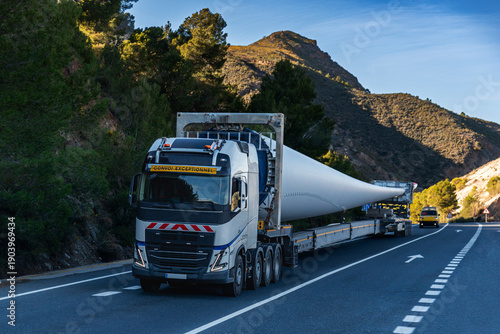 Special transport truck carrying an oversized wind turbine blade on a rural road