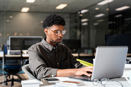Black man working in office using laptop