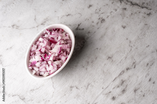 Red onion diced in a bowl on a kitchen bench