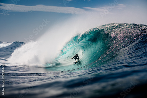 A skilled surfer maneuvering inside a large barrel on a massive wave