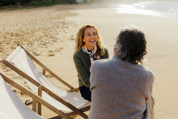 Couple enjoying conversation on beach lounge chairs
