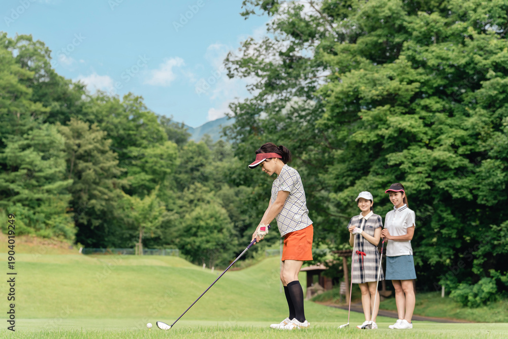 Obraz premium A woman playing golf on a golf course and a female golfer watching her swing