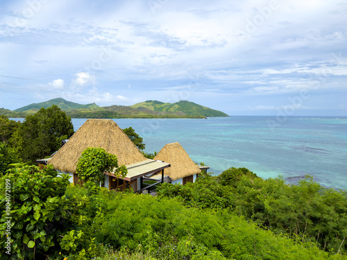 Tableau sur toile Luxury tropical island resort with traditional thatched roof villas overlooking