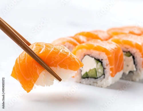 Vibrant salmon sushi roll held by chopsticks, atop white surface, other rolls blurred in background, closeup