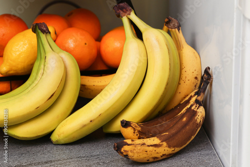 Tableau sur toile Ripe and overripe bananas with oranges on kitchen counter