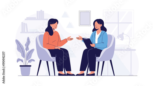 Female psychologist or consultant in blue jacket talking with a woman sitting in armchairs in a quiet professional office environment.
