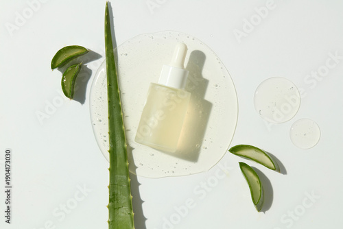 Aloe vera leaves with serum bottle and clear liquid. Natural skincare product composition for beauty advertising