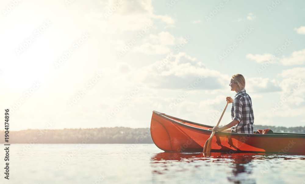 Obraz premium Holiday, woman and peaceful with canoeing on lake for travel adventure, weekend activity and space. Sunshine, person and rowing in boat for vacation journey, nature tourism and break with fresh air