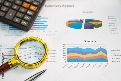 Magnifying glass on graph paper chart; financial development; bank accounts; statistics; economic data; research; analysis; investment.