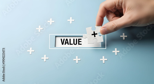 Hand placing puzzle piece with plus sign onto the word VALUE surrounded by plus signs demonstrating added value
