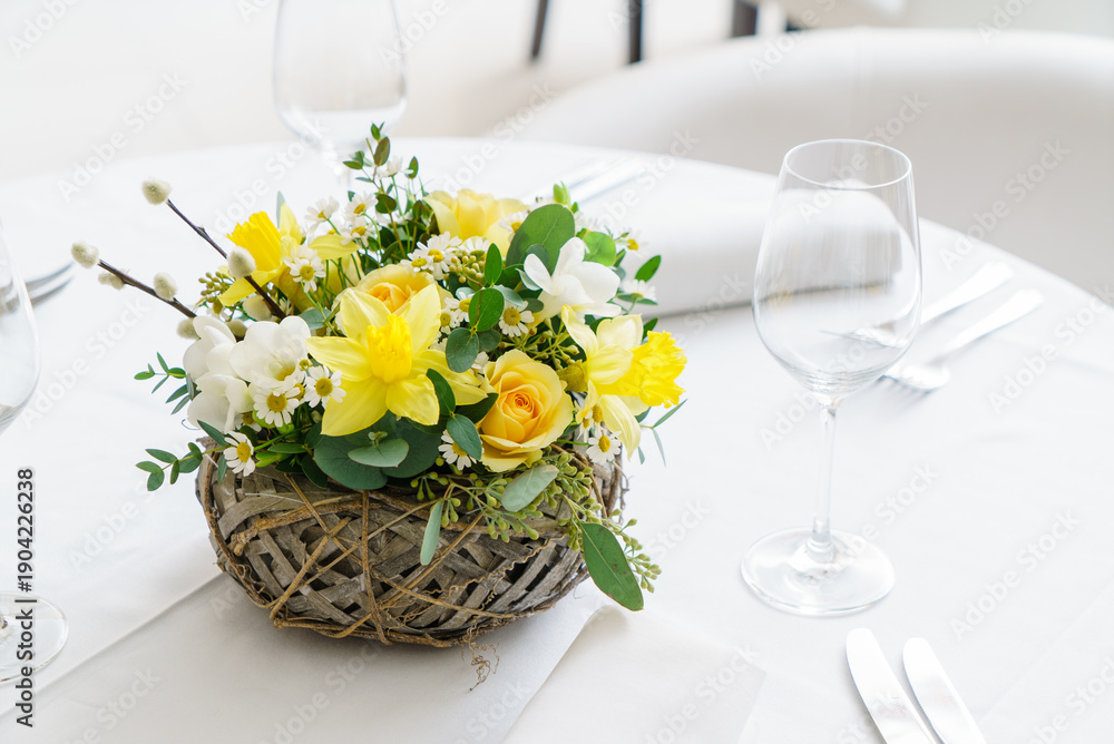 Fototapeta premium Bright yellow flowers and soft white blooms create a festive atmosphere for Easter dining