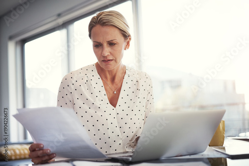 Laptop, woman or worry with documents in home for invoice review, compare client data or remote work. Freelance accountant, mature person and tech with concern for receipts and cash flow verification