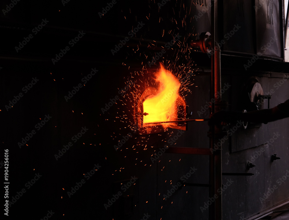 Obraz premium The workers are stirring the coal in the boiler.