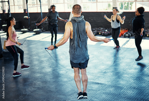 Fotografie Fitness, circle or people in gym class with jump rope, cardio workout or calorie burn in team training