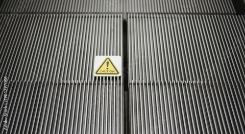 Caution sign on metal accordion background, close-up detail of industrial or architectural metal structure with warning symbol