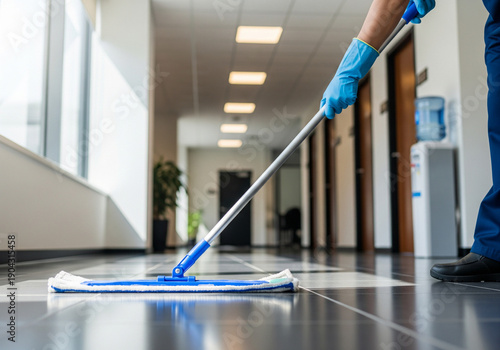 Professional Janitor Mopping the Tiled Floor in a Modern Office Hallway