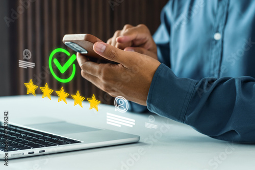 Businessman using a mobile phone giving a five-star verified rating. Concept of customer satisfaction, five star rating on mobile, representing customer feedback, satisfaction review, digital feedback