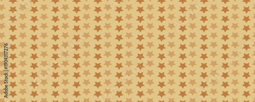 Golden background from metal foil paper with a pattern of sparkling stars closeup. Texture of yellow metallized wrapping holiday paper surface.