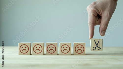 Hand cutting out negative emotions with scissors on wooden blocks