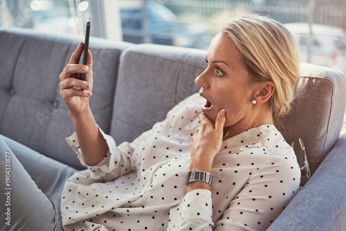 Photos Home, shocked and woman on sofa, smartphone and digital app for social media