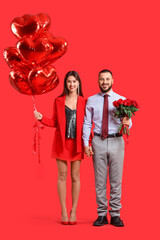 Beautiful young couple with bouquet of red rose flowers and air balloons in shape of heart on color background. Valentine's day celebration