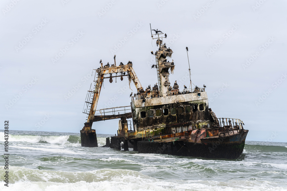 Fototapeta premium The rusted Zeila shipwreck rests along the remote Atlantic coastline of Namibia’s Skeleton Coast. Once a fishing vessel, the abandoned ship now stands as a powerful symbol of the ocean’s strength.