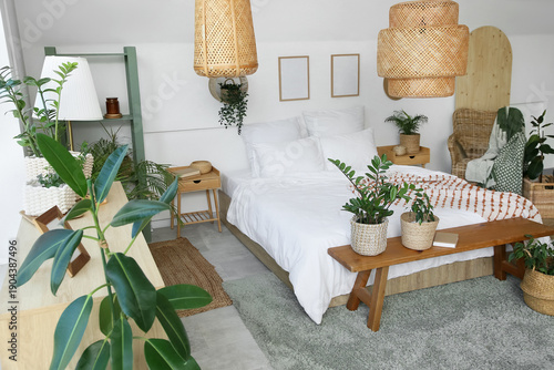 Photography Bed, bench and houseplants in wicker baskets in interior of bedroom