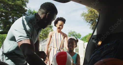 Happy african american family packing car with beach balls on holiday