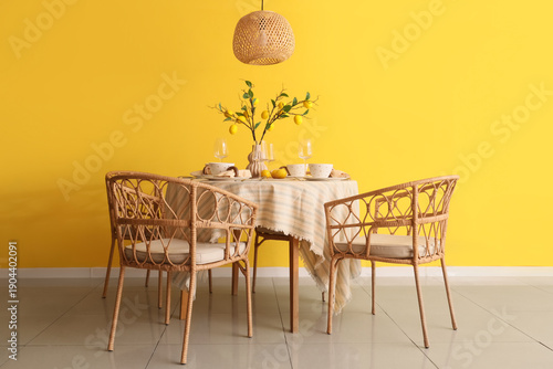Interior of dining room with table setting and beautiful lemon tree branches near yellow wall