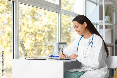 Young female doctor writing...