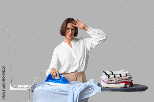 Tired young woman ironing s...