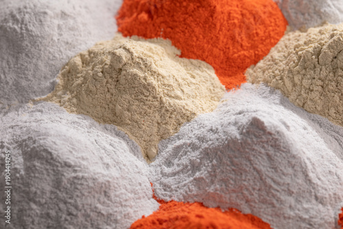 Photography An angled, close-up photo shows three distinct mounds of high-quality nanostructured powder paint in bold orange, bright white, and pale beige