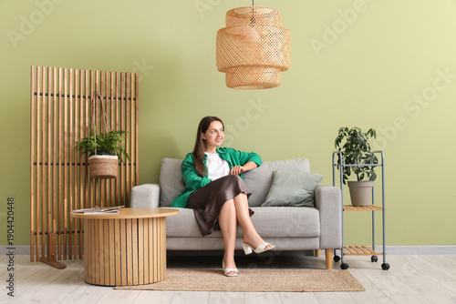 Young woman sitting on sofa...