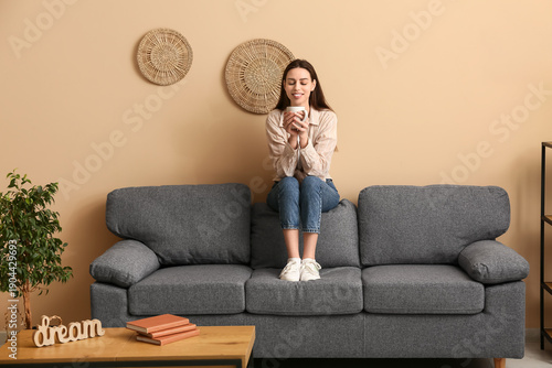 Young woman sitting on sofa...