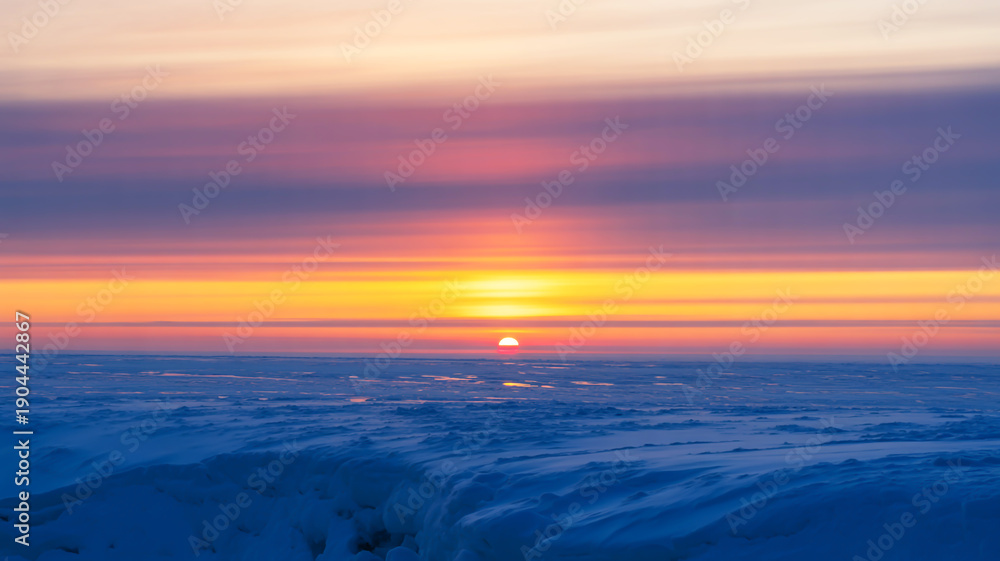 Fototapeta premium Serene sunset over a vast icy landscape, painting the sky with warm hues of orange, pink, and purple