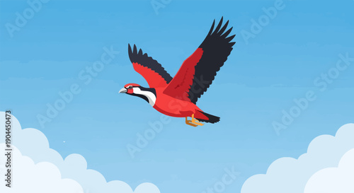A red and black bird with wings spread soars through a bright blue sky