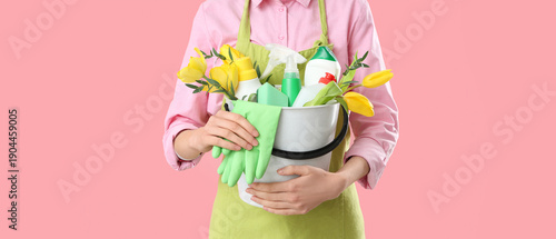 Φωτογραφία Female janitor with cleaning supplies and spring flowers on pink background, clo