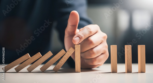Hand stopping a domino effect with finger