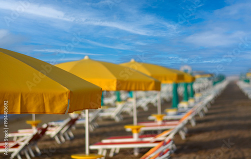 yellow umbrellas open on the beach in front of the sea