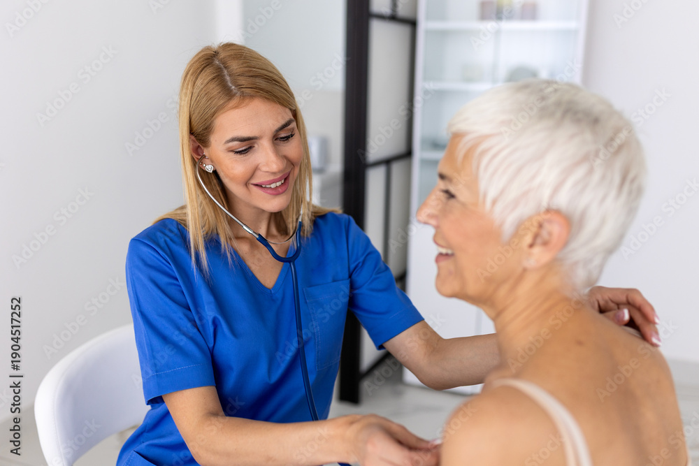 Obraz premium Smiling Female Doctor Using Stethoscope on Senior Patient, Medical Practitioner Performing Heart and Lung Auscultation, Healthcare Checkup for Elderly Woman in Clinic.