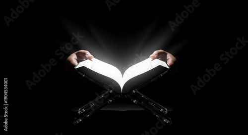 Hands Holding Open Quran with Divine Light Emanating