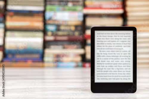 A close-up of an e-book with space for writing on the screen. an e-book against the background of paper books. modern electronic reader. 