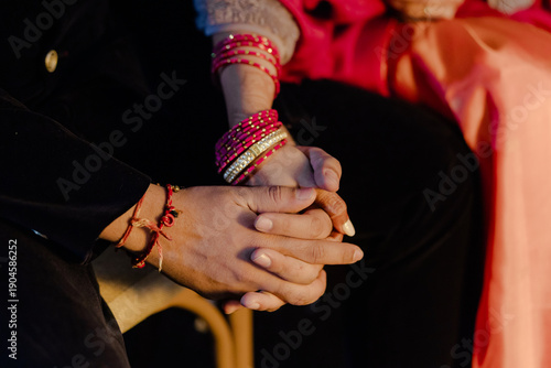 A couple hold hands, symbolizing commitment, love, and togetherness, accentuated by traditional bangles and a promise of a shared future, intimate and heartfelt