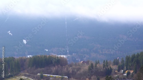 view of Krkonose mountains with moving clouds, commuter train moving in Szklarska Poreba, Poland