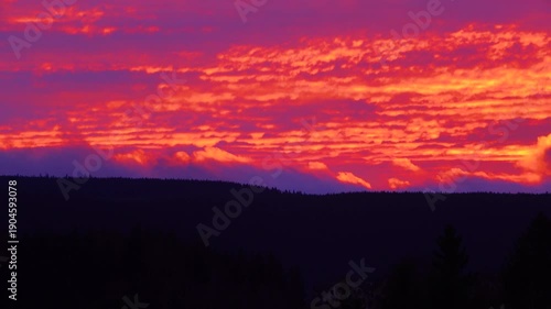 time lapse. moving clouds against a bright sunset with a mountain outline
