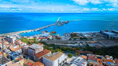 High-angle view of Ortona marina with serene sea, moored boats and detailed port facilities on a sunny day.